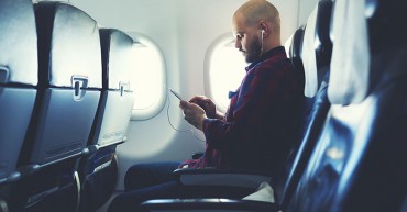 Man listening to music on his phone, on an airplane